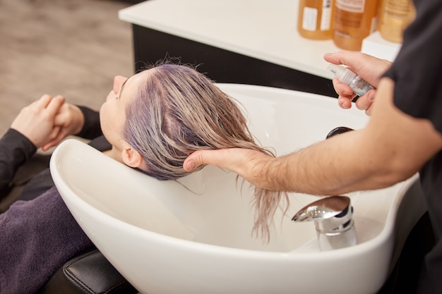 Fryzjer nakłada serum na włosy klienta po farbowaniu i tonowaniu