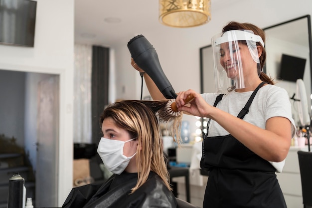 Zdjęcie fryzjer noszący osłonę twarzy i maskę z materiału klienta