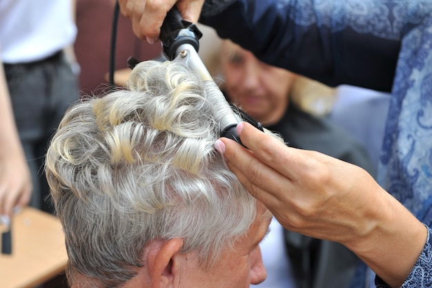 Fryzjer robi fryzurę dla starszej kobiety.