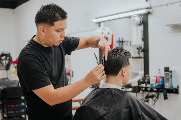 Zdjęcie fryzjer ścina i czesze włosy swojego klienta