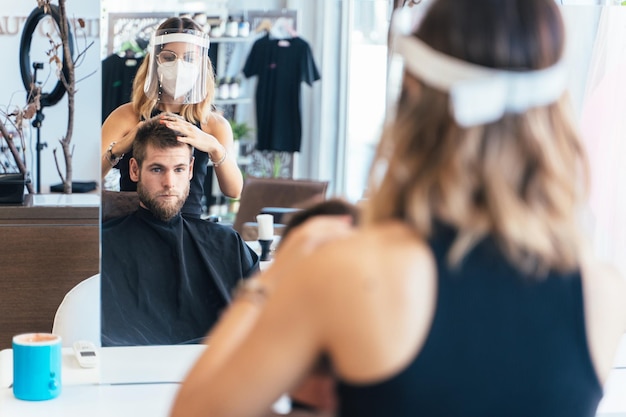 Fryzjer układający włosy mężczyzny w salonie