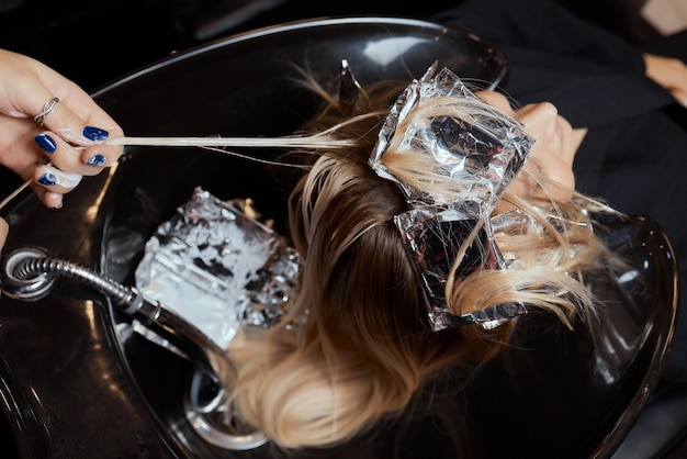 Zdjęcie fryzjer w salonie kosmetycznym myje włosy klienta przed zabiegiem nakładania naturalnych składników przywracających i witamin na włosy i strzyżenie