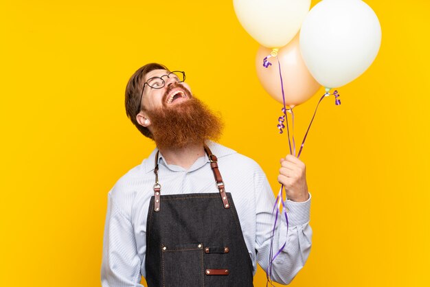 Fryzjer z długą brodą w fartuchu trzymając balony
