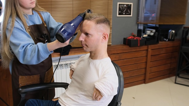 Fryzjerka w salonie kosmetycznym zajmuje się stylizacją włosów dla niepełnosprawnego mężczyzny