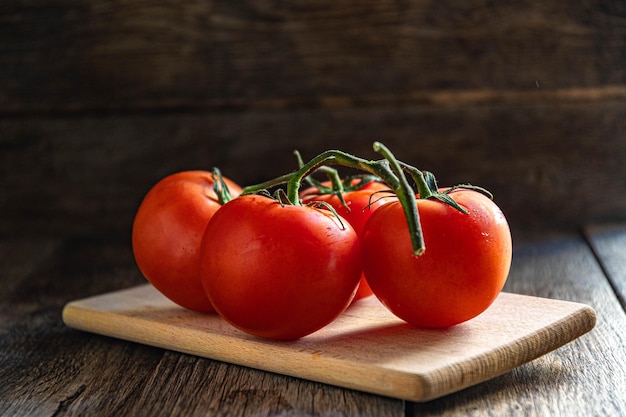 Zdjęcie gałąź dojrzałych pomidorów na desce do krojenia w kuchni