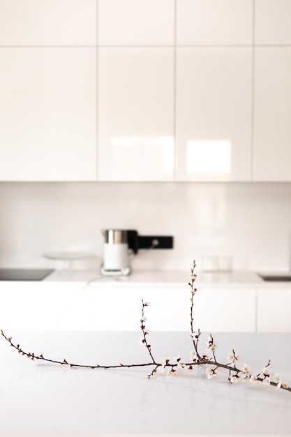 Gałąź kwitnących wiśni wewnątrz na białym domowym stole kuchennym z rozmytym tłem