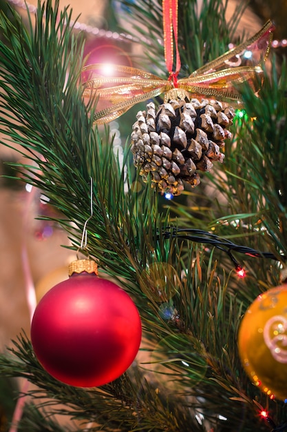 Gałąź świerkowa z kulkami, stożkiem, zabawkami i świątecznymi światłami z iskierkami w tle. Koncepcja Boże Narodzenie i nowy rok.