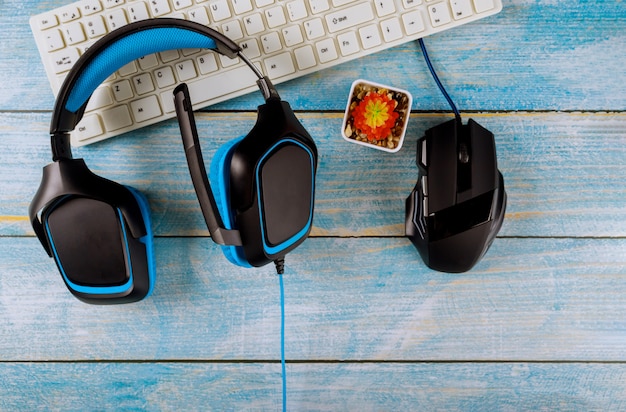 Gamepady słuchawki i klawiatura z myszką na starym drewnianym stole niebieskim