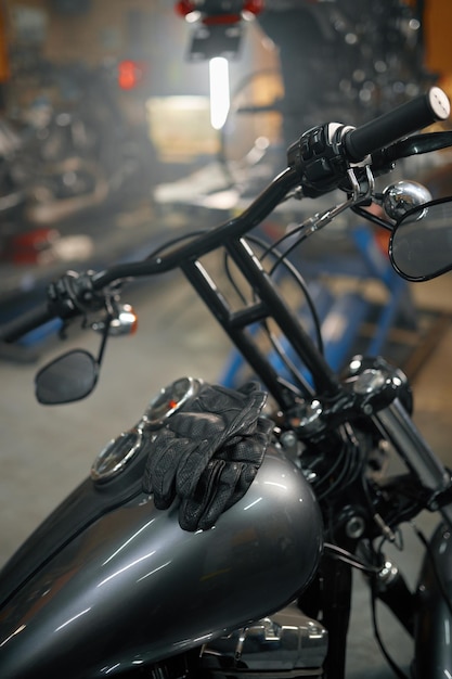Garaż motocyklowy, widok na zbliżenie na skórzanych rękawiczkach motocyklowych na zbiorniku gazu motocyklowego