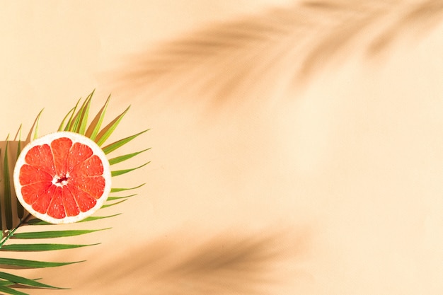 garpefruit i liść palmy na beżowym banerze w tle