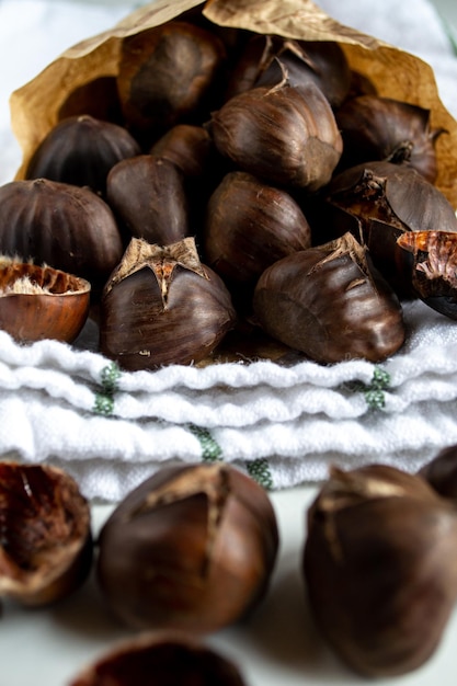 Garść pieczonych kasztanów w papierowej kopercie na ręczniku kuchennym