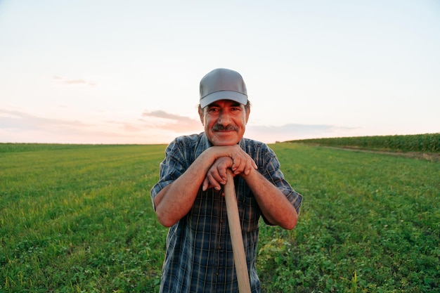 Zdjęcie gdy słońce zachodzi na horyzoncie, zadowolony farmer, wyróżniający się wąsami, oferuje