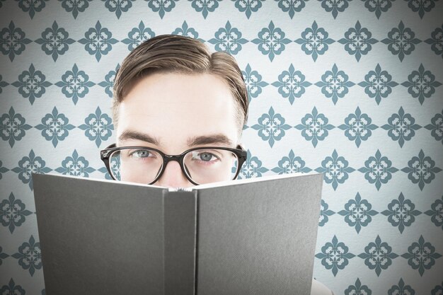 Zdjęcie geeky mężczyzna przegląda książkę przeciw błękitnemu tłu
