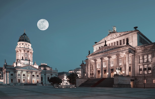 Gendarmenmarkt w Berlinie w nocy z wielkim głupcem Księżyc nad francuskim kościołem Dome