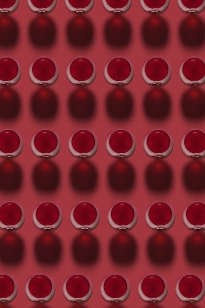 Geometryczny wzór z kieliszków z napojem alkoholowym czerwonego wina na czerwonym tle z twardymi cieniami. Widok z góry.