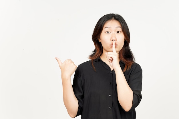Gest Shh prezentujący i wskazujący produkt boczny za pomocą kciuka pięknej azjatyckiej kobiety