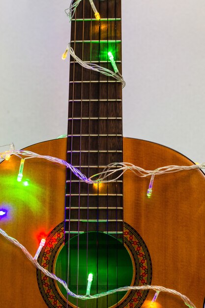 Gitara akustyczna owinięta kolorową girlandą. świąteczny i noworoczny prezent muzyczny jako tło