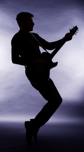 Zdjęcie gitarzysta sylwetka na ciemnoszarym tle