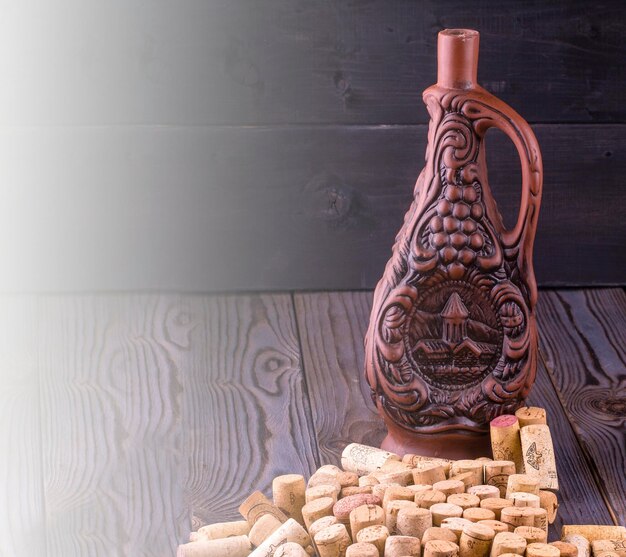 Zdjęcie gliniana butelka wina i korka na ciemnym drewnianym stole w łagodnym świetle słonecznym