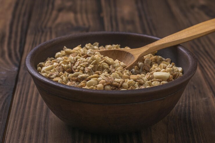 Zdjęcie gliniana miska z muesli i drewnianą łyżką na drewnianym stole