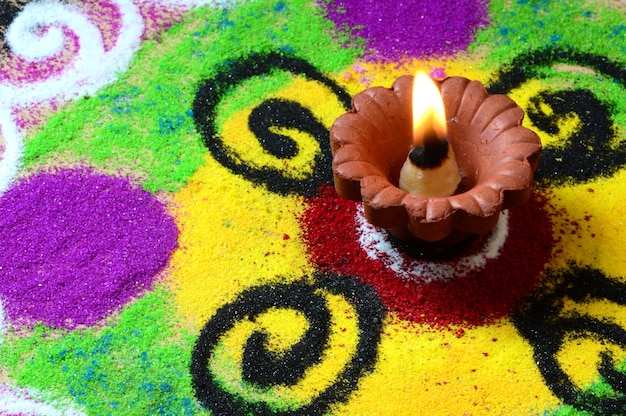 Gliniane lampy diya zapalone podczas obchodów diwali, w tle Rangoli