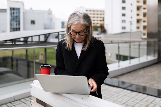 Głowa dorosłej kobiety pracująca na laptopie na zewnątrz