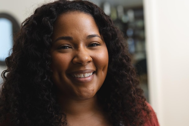 Głowa szczęśliwej afroamerykańskiej kobiety z kręconymi włosami uśmiechającej się w słonecznym domu