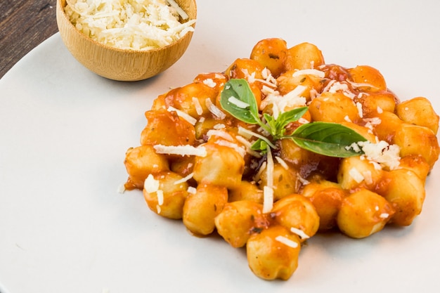 Gnocchi z sosem sokowym z tartym serem i bazylią podawane na talerzu Ostrość selektywna Widok z góry