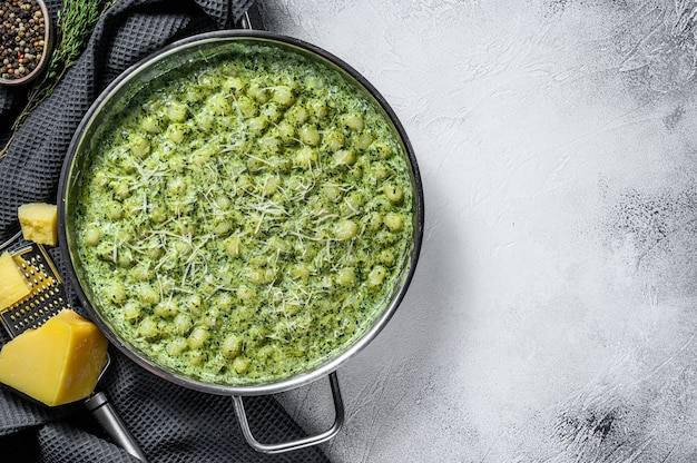 Gnocchi ziemniaczane z pesto, parmezanem i szpinakiem. Włoski makaron. szare tło. Widok z góry. Skopiuj miejsce