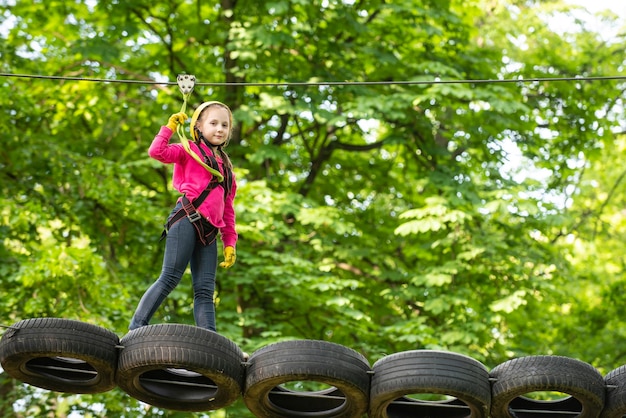 Zdjęcie go ape adventure maluch wspina się po linowej konstrukcji placu zabaw urocze dziecko podczas wspinaczki w sprzęcie zabezpieczającym w domku na drzewie lub w parku linowym wspina się po linie