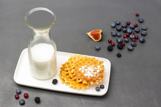 Gofry i mleko w butelce na białym talerzu Figi i jagody na stole