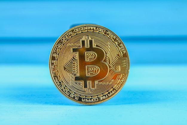 Gold coin crypto waluta bitcoin na niebieskim stole.