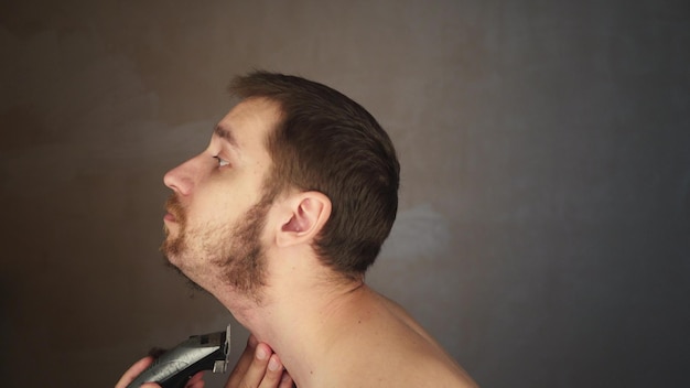 golenie twarzy elektryczna maszynka do golenia przycinanie zarostu na twarzy przez golarkę zarost człowiek proces golenia brody nieogolony facet przycinanie brody mężczyzna golenie twarzy z bliska mężczyzna przycinanie brody golenie na sucho golarka elektryczna