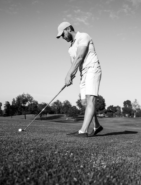 Golfer grający w golfa wieczorem pole golfowe. Mężczyzna gra w golfa na polu golfowym w słońcu.