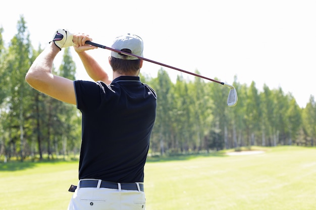 Golfer uderza strzałem z toru wodnego w kierunku domu klubowego.