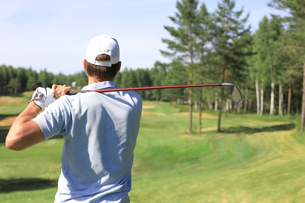 Golfer uderza w strzał z toru wodnego w kierunku domu klubowego.