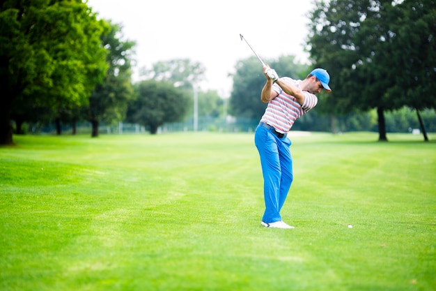 Golfista ćwiczący i koncentrujący się przed i po strzale podczas ładnego słonecznego dnia