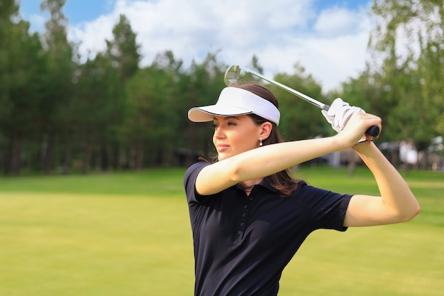 Golfista kobieta uderza w toru wodnego w kierunku domu klubowego.