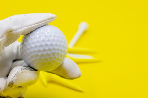 Golfista trzyma trójniki golfowe na żółtym tle