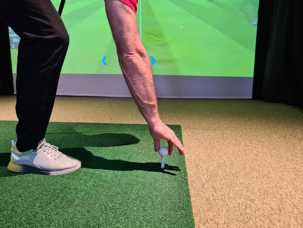Golfista w studio położył piłkę golfową na tee, aby grać na symulatorze