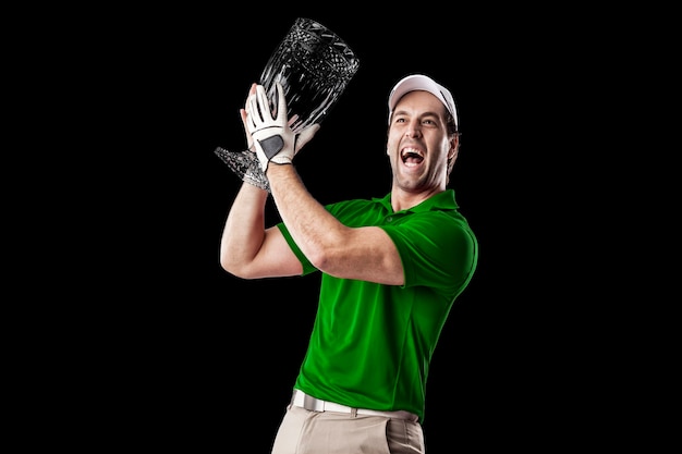 Golfista w zielonej koszuli świętuje ze szklanym trofeum w dłoniach, na czarnym tle.