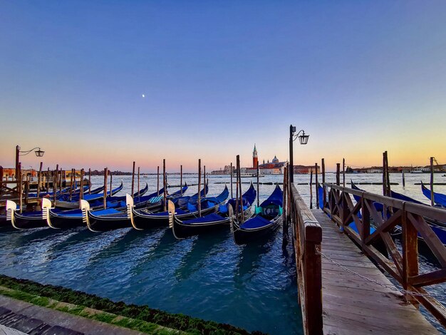Gondola zacumowana w morzu na czyste niebieskie niebo w Wenecji o zachodzie słońca