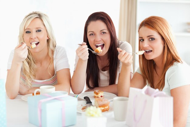 Goodlooking Kobiety siedzą przy stole jedzenia ciasta