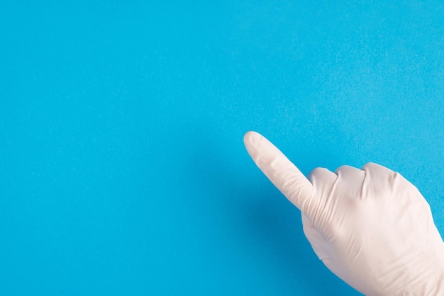 Góra nad głową bliska pov pierwsza osoba przycięty widok zdjęcie lekarza ręka w białej lateksowej rękawiczce wskazujący palec wskazujący na wybranym miejscu na białym tle jasny kolor niebieskie tło