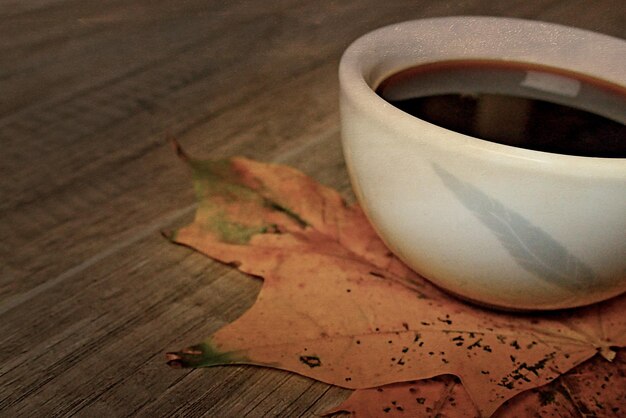 gorąca jesienne czarna kawa espresso na drewnianym stole i jesienne liście klonu