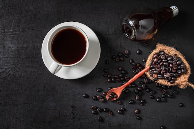 Gorąca kawa i surowe kawowe fasole na czarnym tle.
