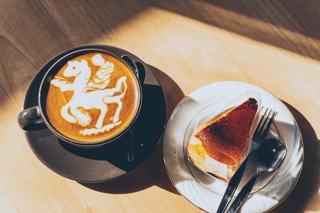 Gorąca kawa latte z latte art w postaci pianki mleka konia w kubku kubka i domowe ciasto czekoladowe na drewnianym biurku na widoku z góry jako śniadanie w kawiarni w kawiarni podczas koncepcji pracy biznesowej