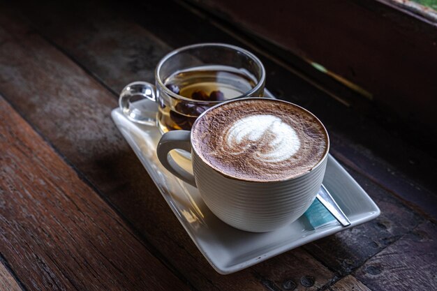 Gorąca kawa latte z mleczną pianką latte art w filiżance kubku gorąca herbata na drewnianym biurku na widoku z góry jako śniadanie w kawiarni w stylu Vintage sklep w kawiarni podczas koncepcji pracy biznesowej