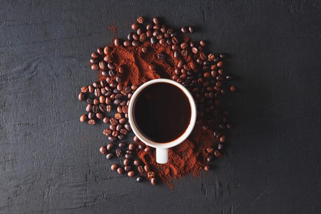 Gorąca kawa z proszkiem kawy i ziarnami kawy na czarnym tle