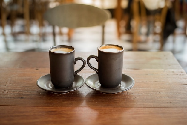 Gorąca latte sztuka z czarnym szkłem na drewnianym stole